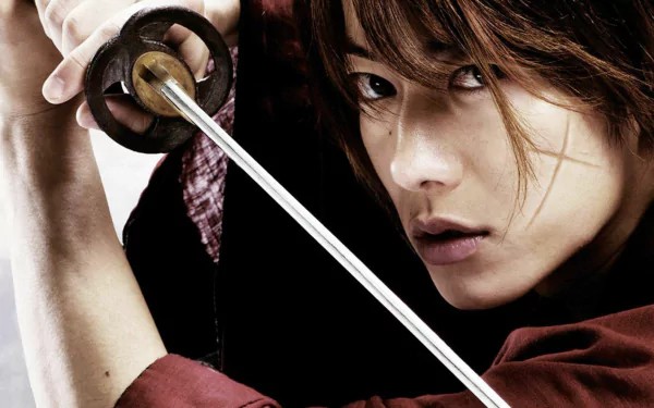 HD PC desktop wallpaper from the Rurouni Kenshin movie: close-up of a determined swordsman gripping a katana, red kimono, intense gaze and dramatic lighting.