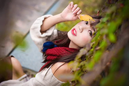 2K Quad HD desktop wallpaper of an Asian brunette model lying down, brown-eyed woman in a scarf with red lipstick, holding a yellow leaf.