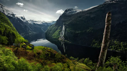 HD PC desktop wallpaper of nature: a fjord framed by towering mountains and trees, their forms mirrored in a calm river reflecting snowy peaks and green slopes.