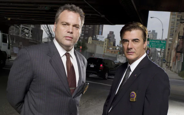 HD PC desktop wallpaper: two suited detectives from the TV show Law & Order: Criminal Intent stand beneath a city overpass, facing camera with serious expressions.