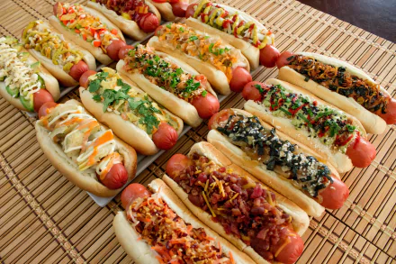 HD desktop wallpaper featuring an array of colorful hot dogs topped with various fresh ingredients on a woven placemat.