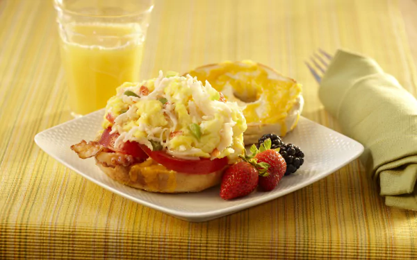 HD PC desktop wallpaper: bagel lunch — open bagel sandwich with scrambled eggs, tomato and bacon on bread, fresh strawberries and blackberries, and a glass of orange juice.