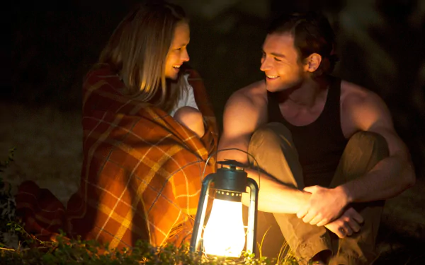 HD desktop wallpaper from the movie The Choice: two people sit by a glowing lantern at night, wrapped in a blanket, sharing a warm, smiling moment.