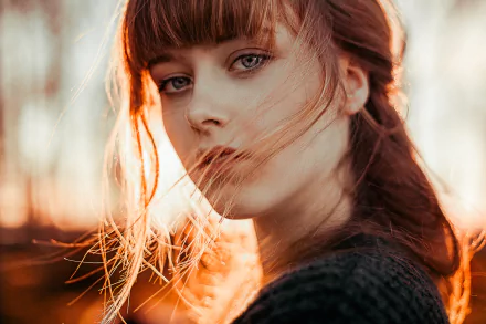 A high-definition desktop wallpaper featuring a redheaded woman with blue eyes, looking directly at the camera. The soft lighting and her striking features create a captivating and serene portrait.