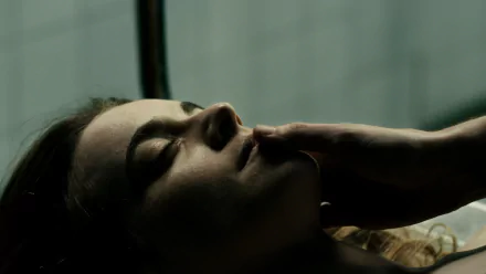 HD PC desktop wallpaper from the movie The Corpse of Anna Fritz, showing a close-up of a woman’s face lying still with a hand gently touching her lips.