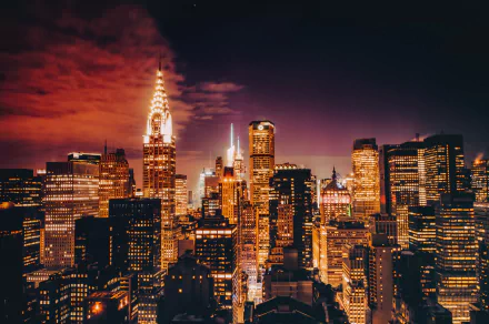 HD PC wallpaper: Manhattan skyline at night in New York, USA, featuring the illuminated Chrysler Building and surrounding man-made skyscrapers with glowing city lights.