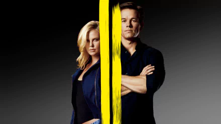 HD desktop wallpaper for the 2003 heist film The Italian Job: a woman and a man stand side-by-side split by a vertical yellow paint stripe on a gray background.