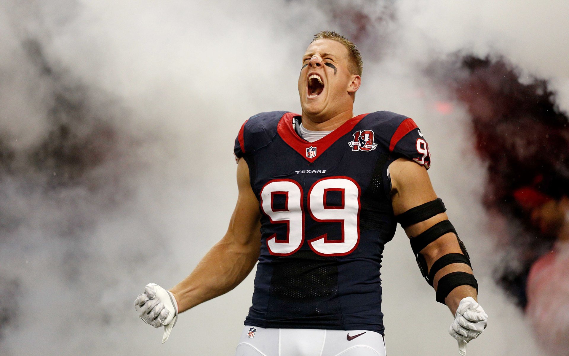 Houston Texans player J.J. Watt in full gear celebrates passionately on an HD sports desktop wallpaper with smoky background effects.