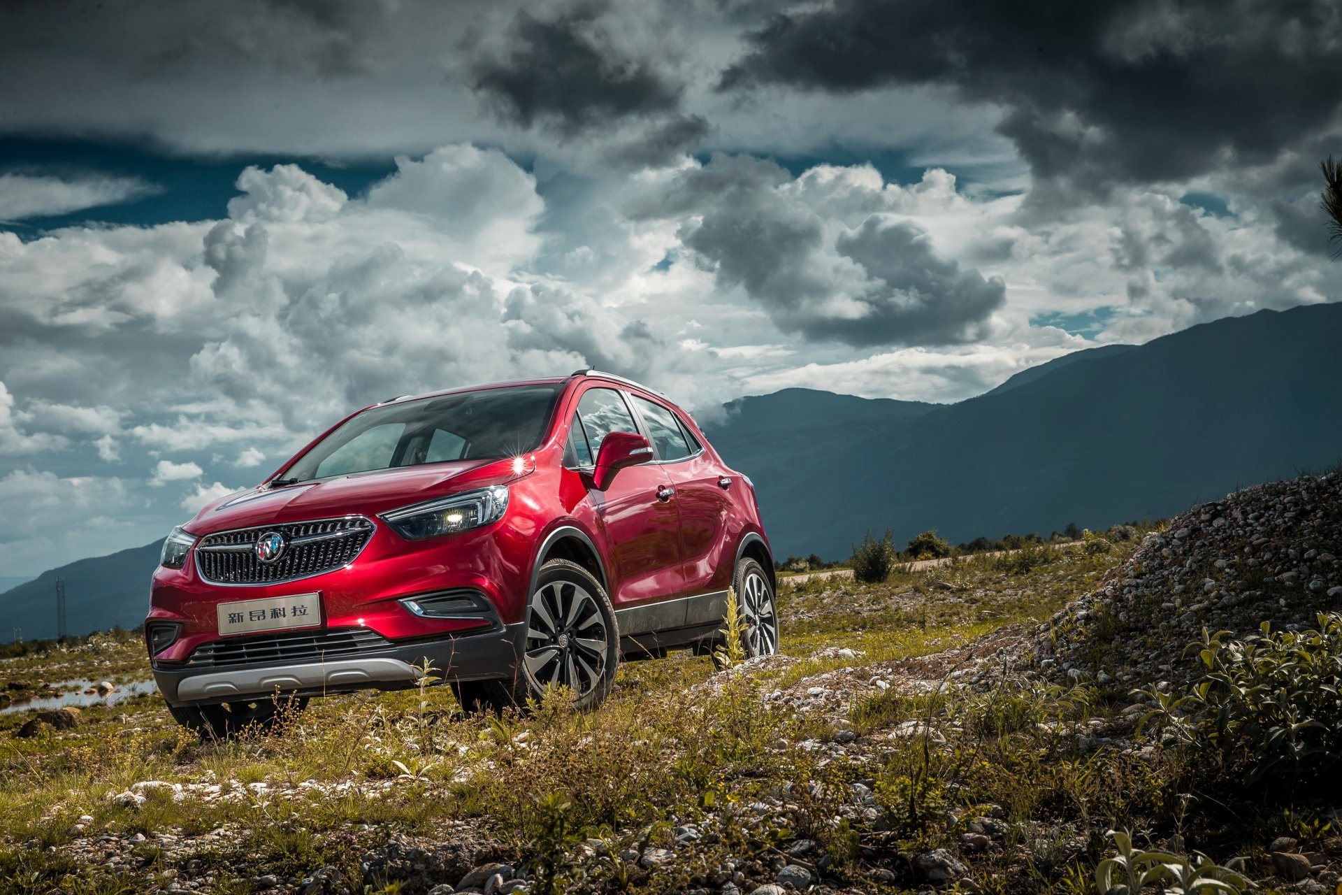 Red Opel Mokka SUV parked on rugged terrain under a dramatic cloudy sky, captured in 4K Ultra HD for a PC desktop wallpaper background.