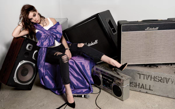HD desktop wallpaper of brunette singer and actress with brown eyes, wearing a necklace and a purple dress, surrounded by vintage Marshall speakers and a boombox.