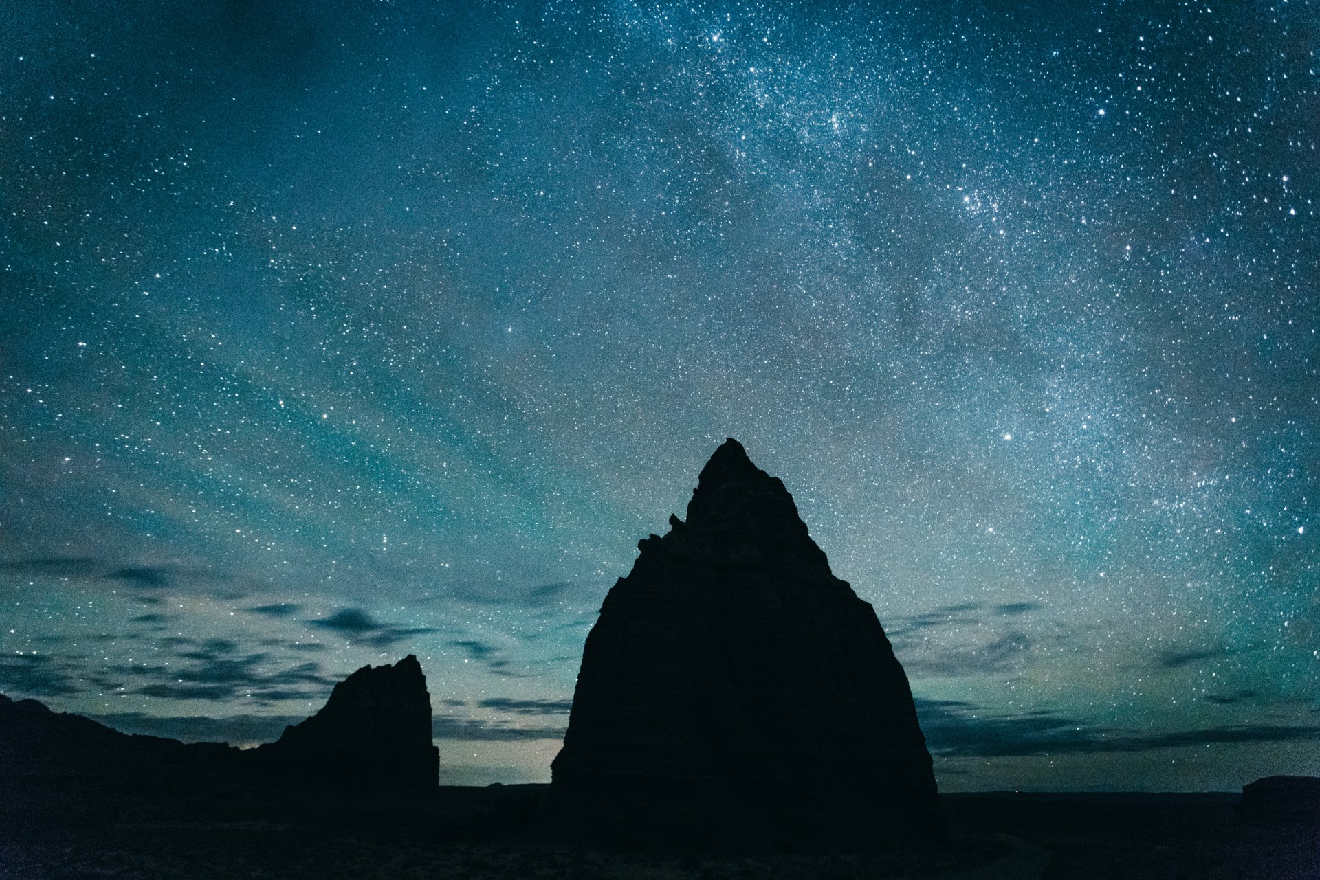 Silhouette of rocky formations under a starry night sky, creating a serene and breathtaking natural view. HD desktop wallpaper and background.