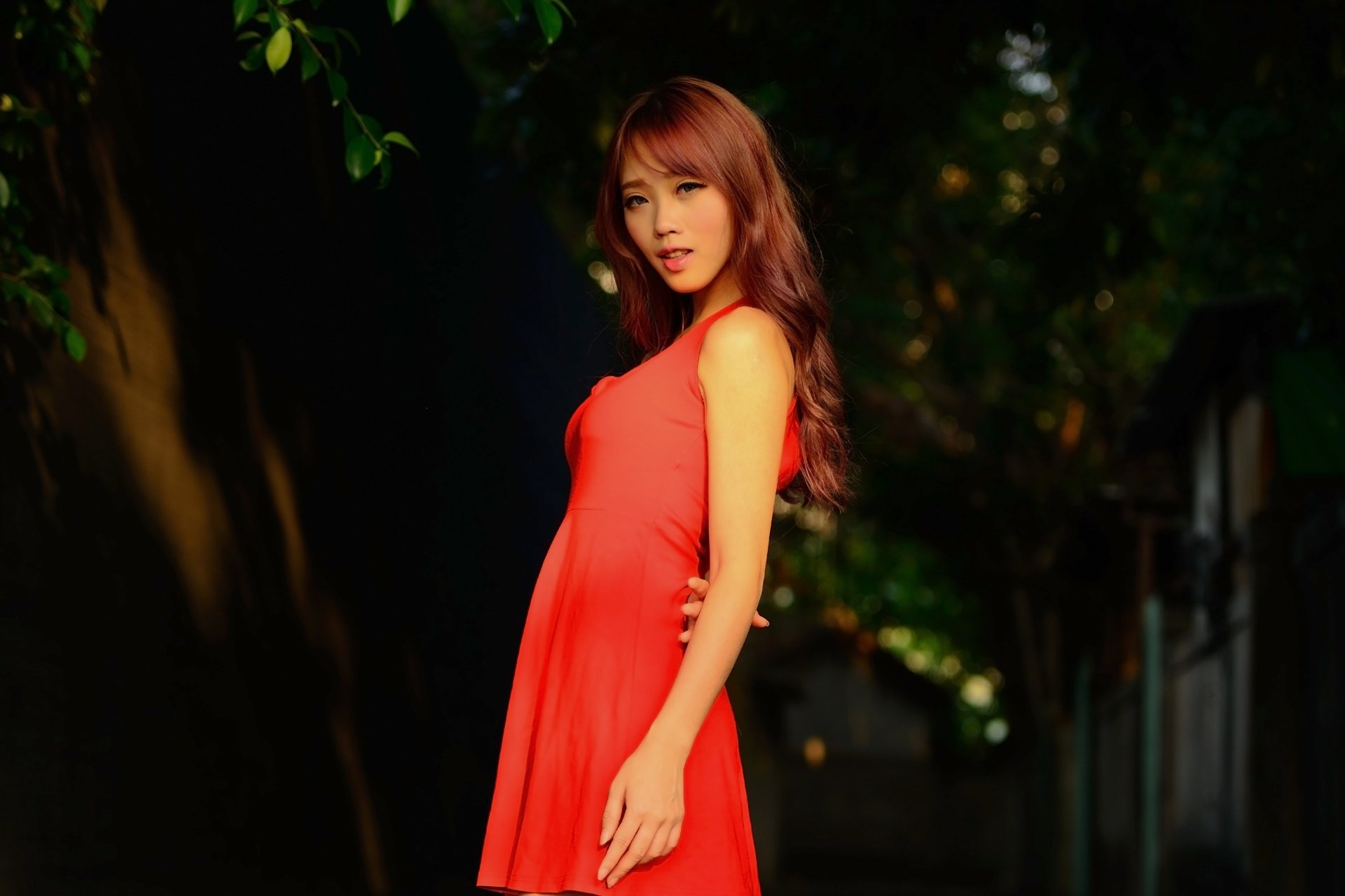 Asian woman model in a flowing red dress poses outdoors, bathed in natural light, captured in stunning 4K Ultra HD for a vibrant PC desktop wallpaper.