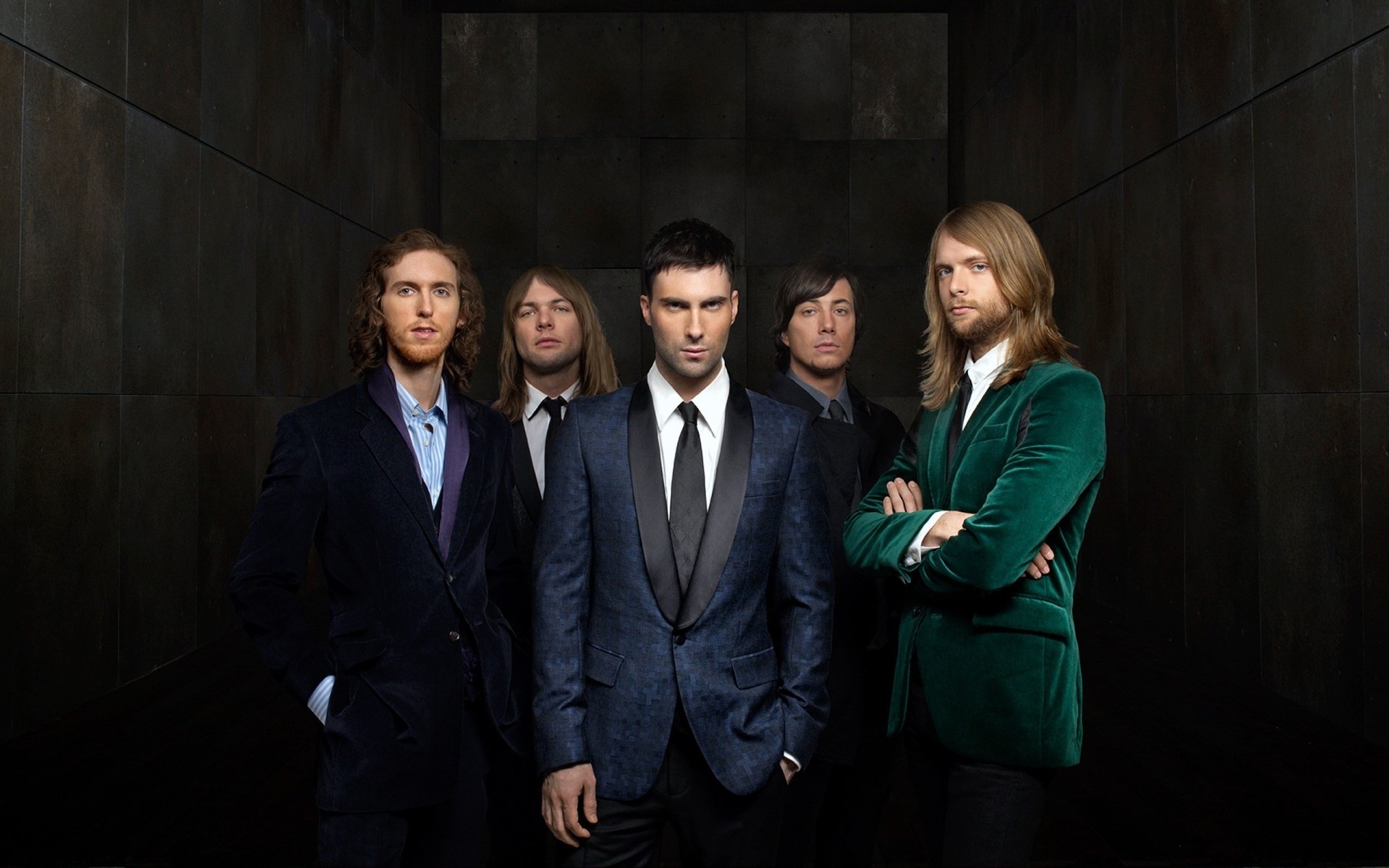 HD wallpaper featuring the band Maroon 5 posing in suits against a dark wooden backdrop.