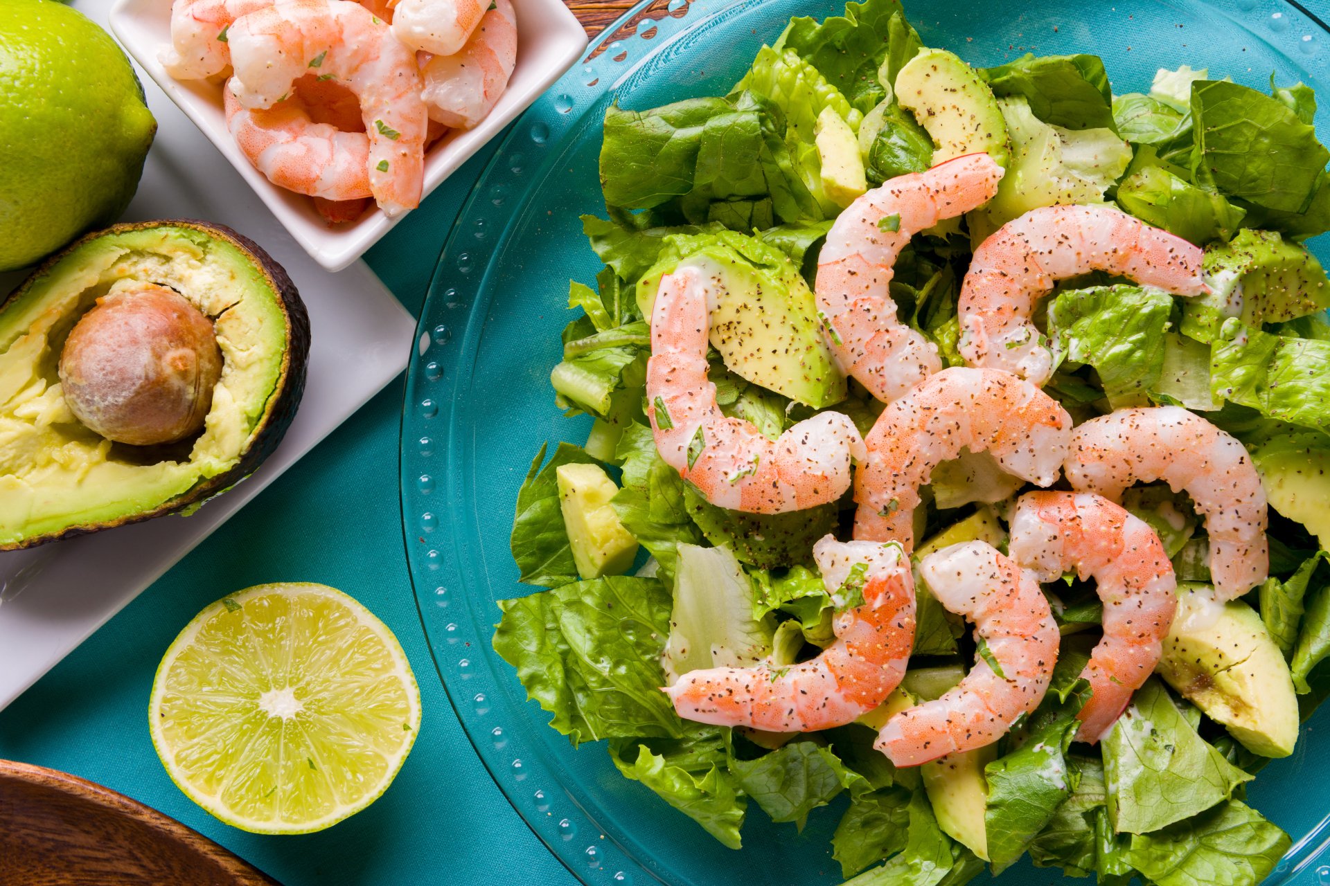 Fresh shrimp and avocado salad on a blue plate, accompanied by halved avocado and lime, captured in vibrant 8K Ultra HD detail.