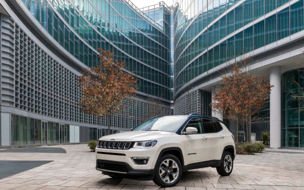 White Jeep Compass SUV parked in front of modern glass office buildings, captured in 4K Ultra HD for a PC desktop wallpaper and background.