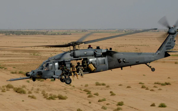 Military Sikorsky UH-60 Black Hawk helicopter flying over a desert landscape, featured in an HD PC desktop wallpaper and background.