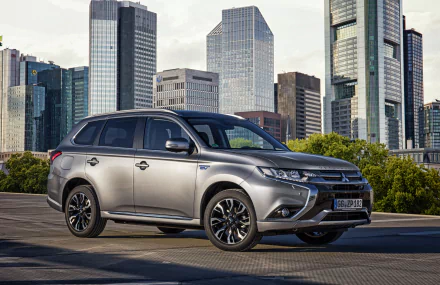 Silver Mitsubishi Outlander SUV parked in front of a city skyline, captured in 4K Ultra HD for a PC desktop wallpaper background.