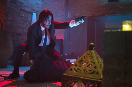Keanu Reeves as John Wick in a dramatic, dimly lit scene, aiming a gun while crouched over an opponent, captured in 4K Ultra HD for a PC desktop wallpaper.
