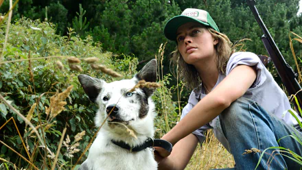 HD desktop wallpaper featuring Margot Robbie from the movie Z for Zachariah, sitting outdoors with a dog against a lush green background.