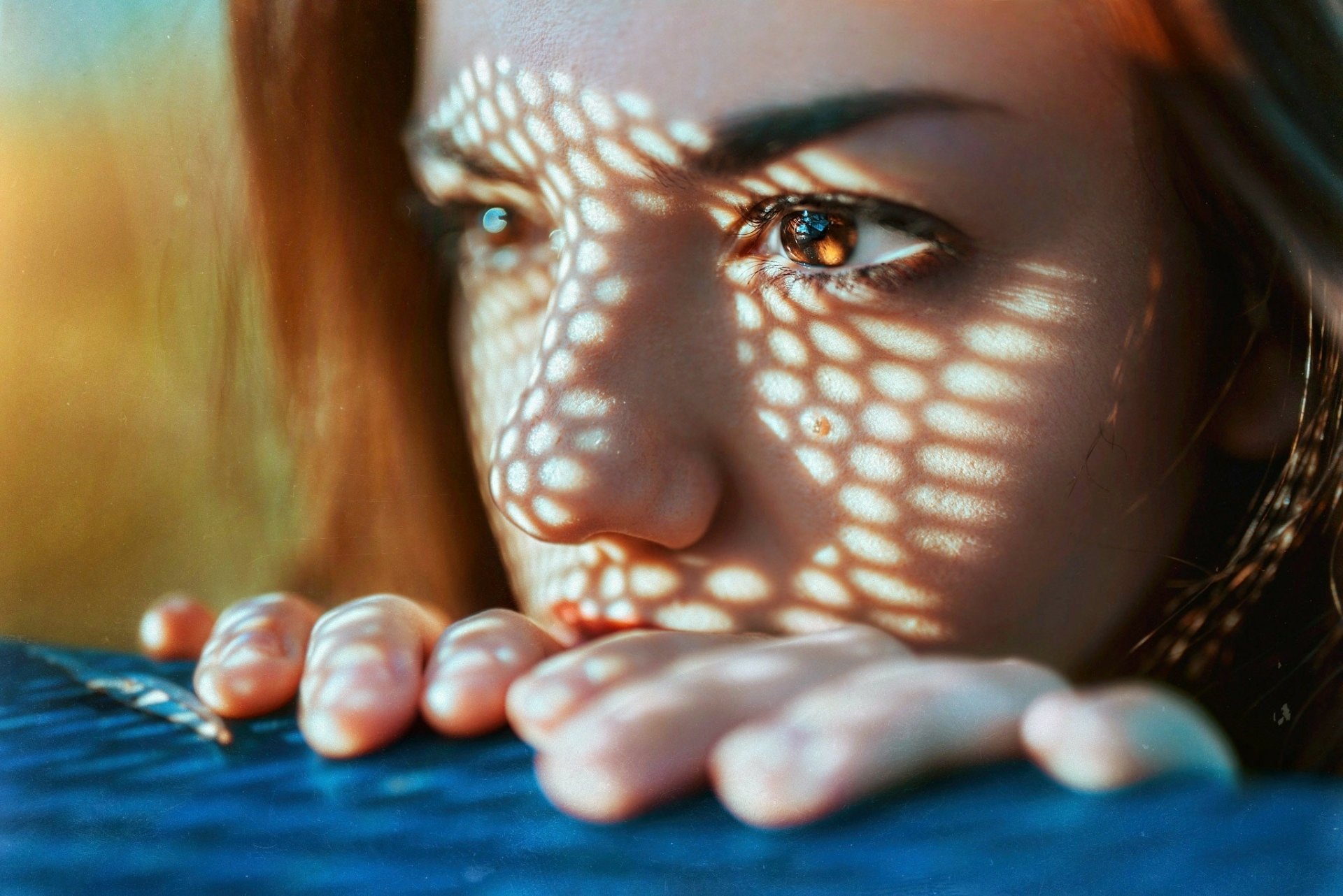Close-up of a woman's face with brown eyes, patterned light across her skin and fingers; HD PC desktop wallpaper and background.