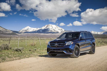 A black Mercedes-Benz GL-Class SUV parked on a dirt road with snow-capped mountains and a blue sky in the background, presented as a 4K Ultra HD desktop wallpaper.