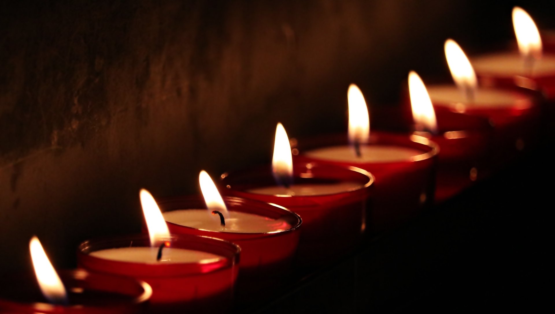 A row of lit red candles with glowing flames captured in detailed photography, presented as a 4K Ultra HD PC desktop wallpaper and background.