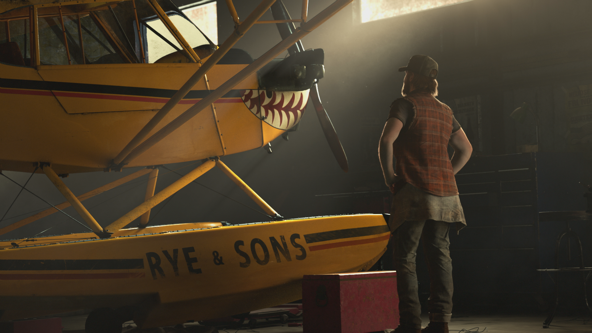An HD desktop wallpaper featuring a scene from the video game Far Cry 5, showcasing a character standing beside a yellow seaplane with Rye & Sons written on the side, in a dimly lit hangar.