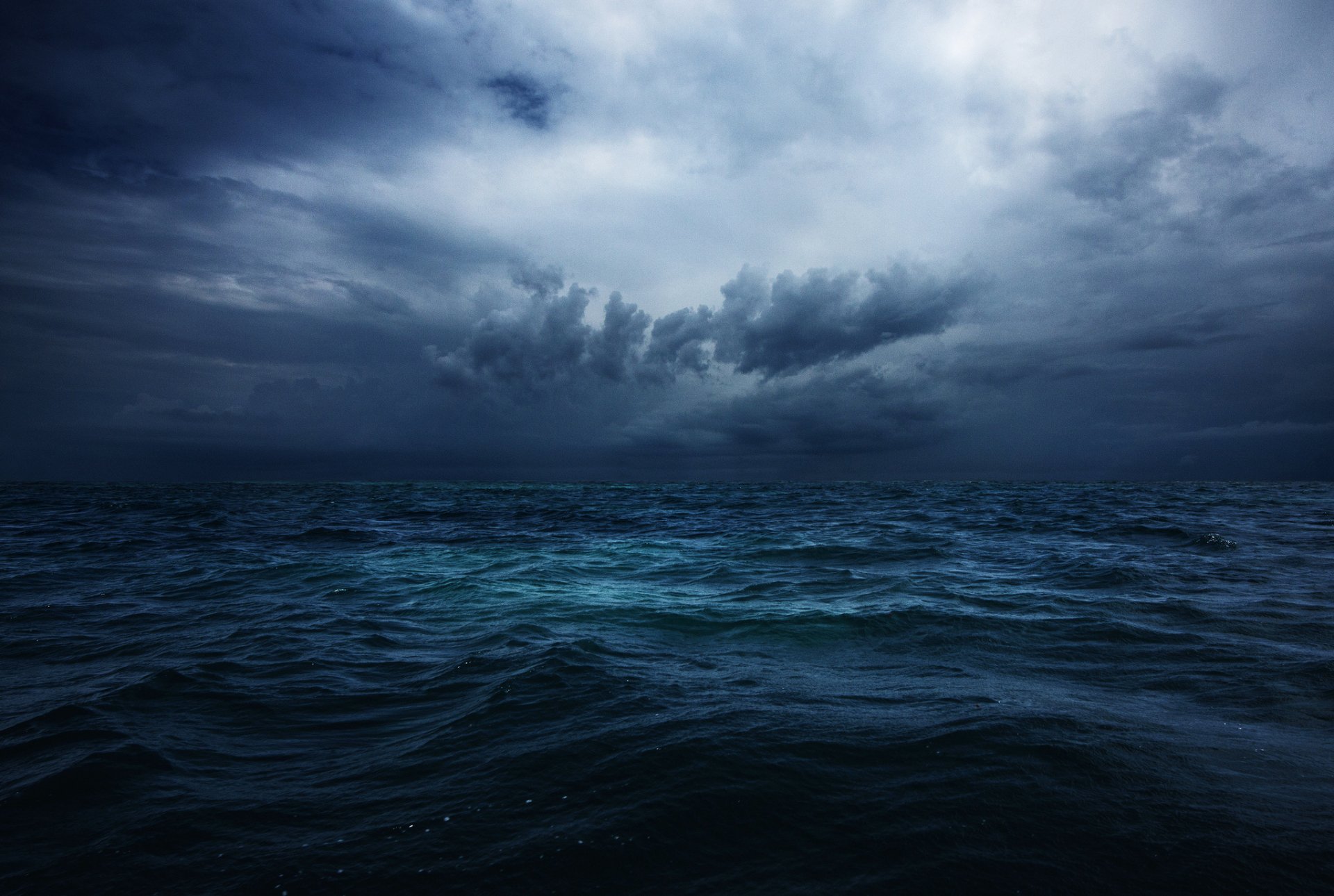 HD desktop wallpaper showing a dramatic ocean scene with dark clouds filling the sky above the horizon over the vast sea, capturing nature’s moody atmosphere.