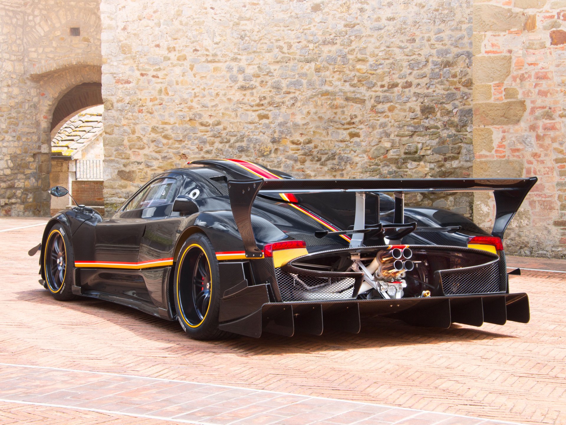 Black Pagani Zonda R supercar rear three-quarter view by stone walls — HD PC desktop wallpaper/background.
