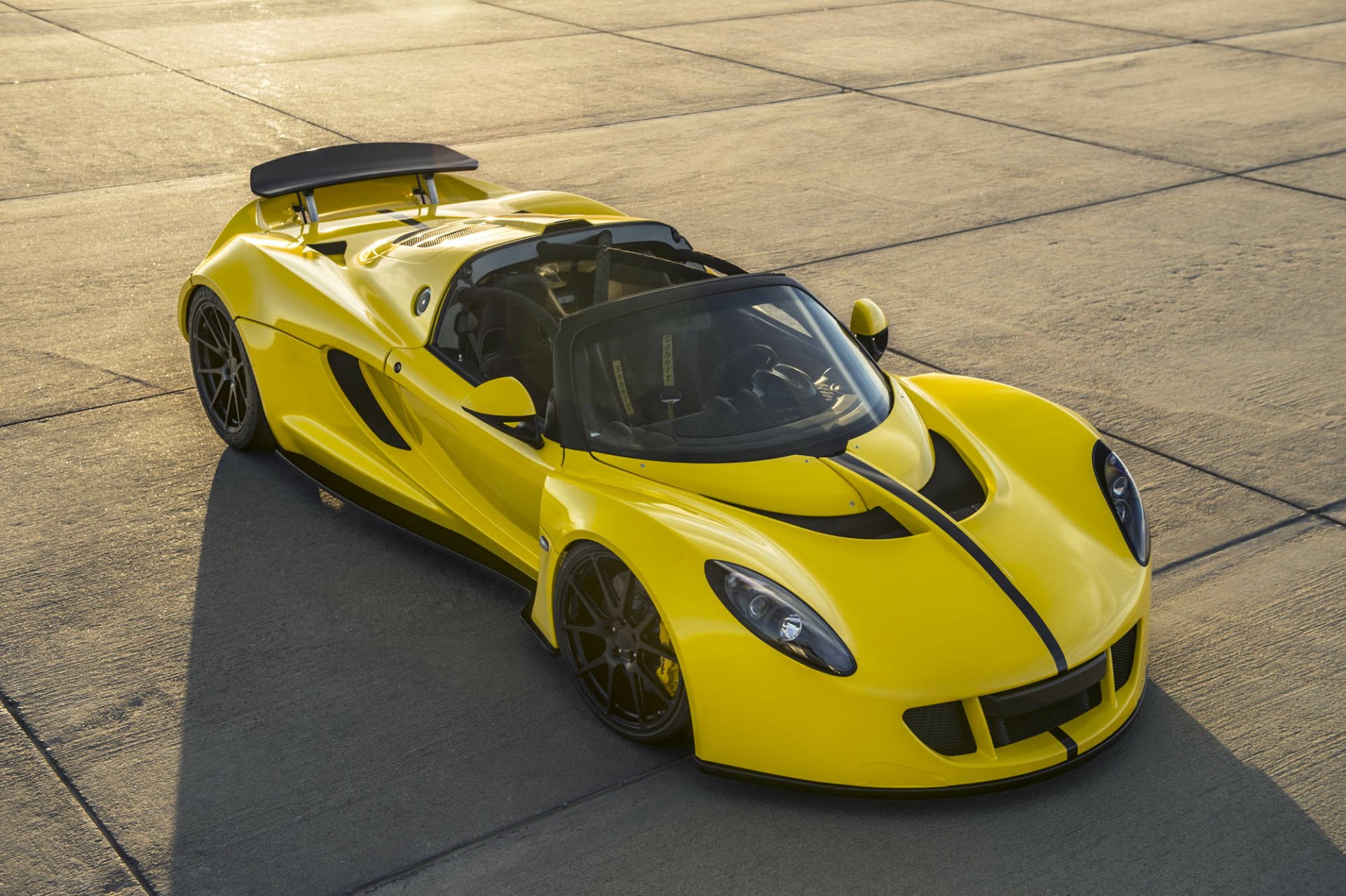 Yellow Hennessey Venom GT Spyder supercar vehicle on sunlit concrete, three-quarter overhead view — HD PC desktop wallpaper and background.