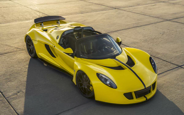 Yellow Hennessey Venom GT Spyder supercar vehicle on sunlit concrete, three-quarter overhead view — HD PC desktop wallpaper and background.