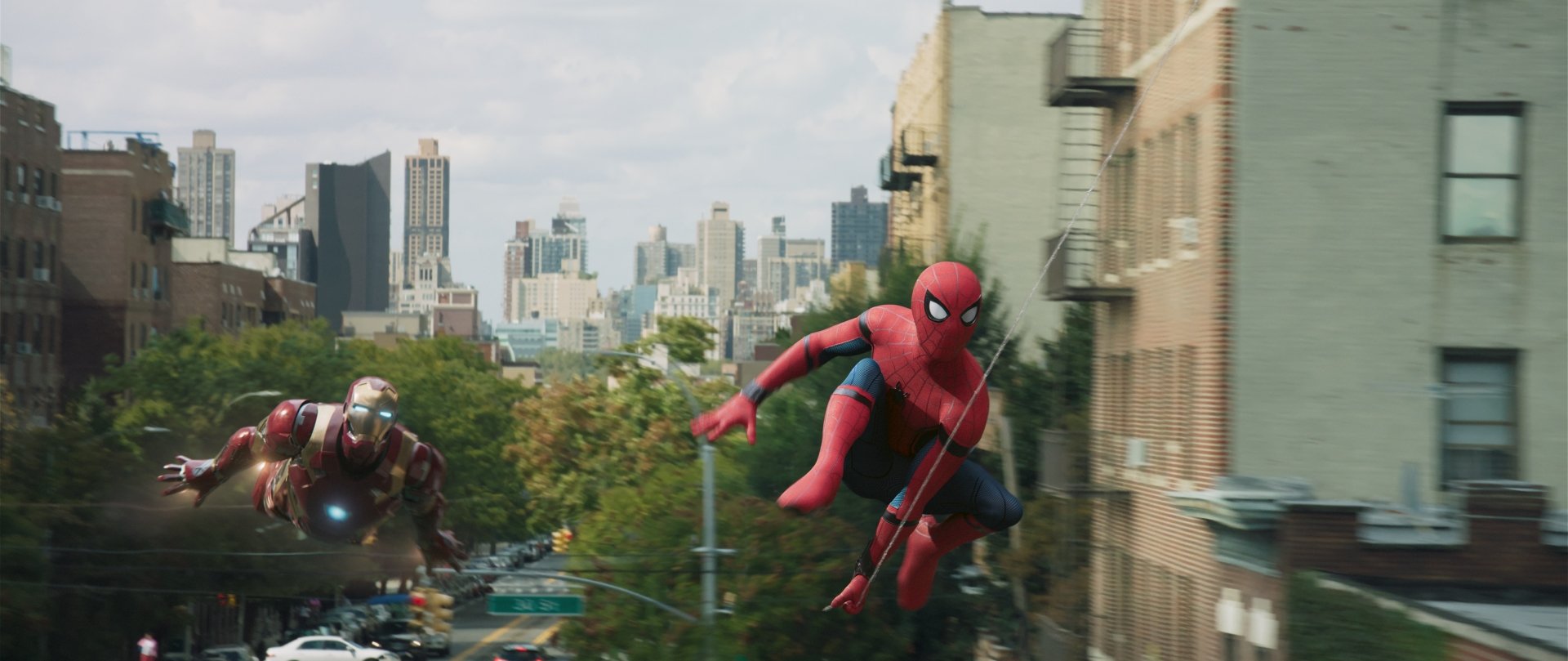 HD desktop wallpaper featuring Spider-Man swinging across a cityscape with Iron Man in the background, from the movie Spider-Man: Homecoming.