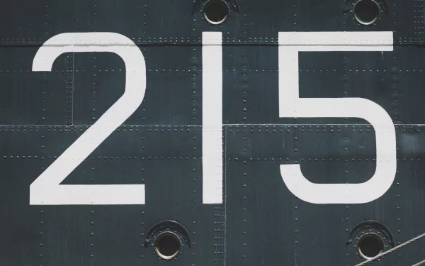 A HD desktop wallpaper featuring the industrial number 215 in bold white on a textured dark grey metal surface with rivets.