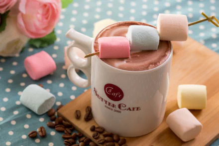HD desktop wallpaper featuring a still life of a cup of hot chocolate topped with pastel marshmallows, surrounded by scattered marshmallows and coffee beans on a polka dot surface.