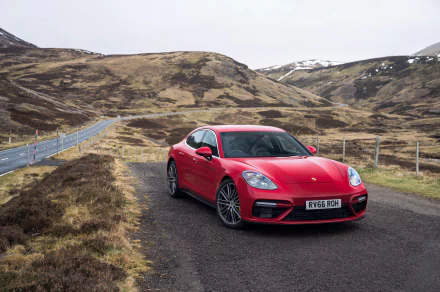 Red Porsche Panamera Turbo parked on a rural road with rugged hills in the background, captured in 4K Ultra HD for a PC desktop wallpaper.