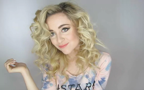 HD desktop wallpaper and background featuring a smiling person with curly blonde hair, wearing a tie-dye shirt.
