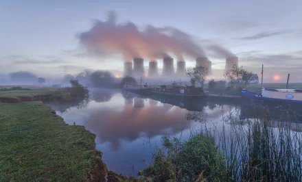 HD desktop wallpaper of a nuclear power plant with smoke rising from cooling towers, reflected in a calm river.