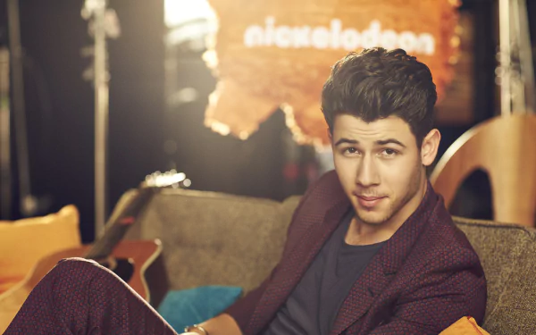 HD wallpaper featuring a person relaxing on a couch with a Nickelodeon sign in the background.