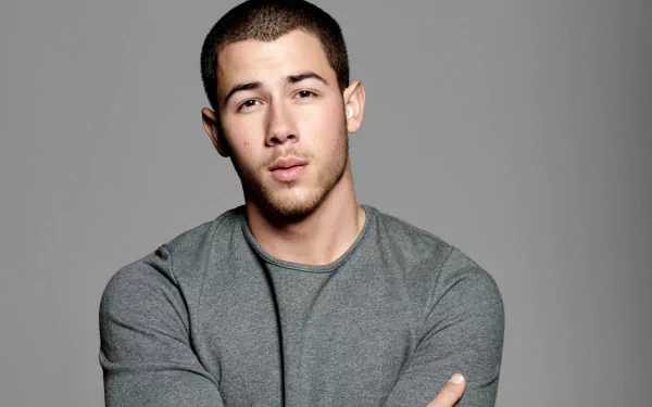 HD desktop wallpaper featuring a man in a gray shirt with a neutral expression, posing for the camera.