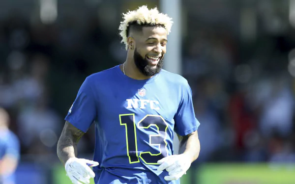 HD wallpaper featuring New York Giants player Odell Beckham Jr. in a blue NFC #13 jersey, smiling on the field.