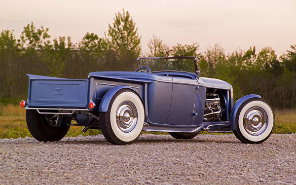 Blue vintage Ford Roadster Pickup hot rod vehicle with whitewall tires on gravel at sunset — HD PC desktop wallpaper/background.