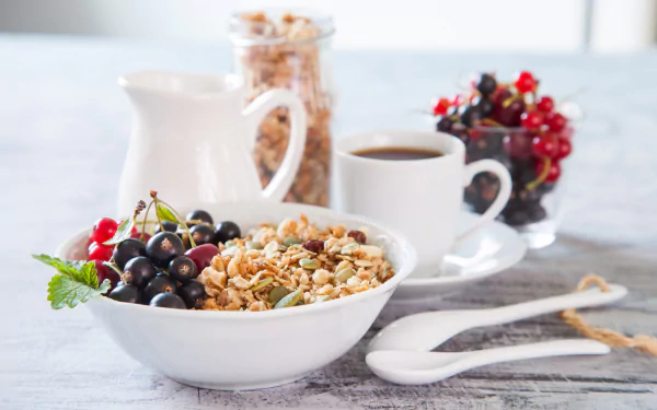 4K Ultra HD PC desktop wallpaper: breakfast still life — a bowl of muesli topped with red and black berries, a cup of coffee, milk jug and jar on pale wood.