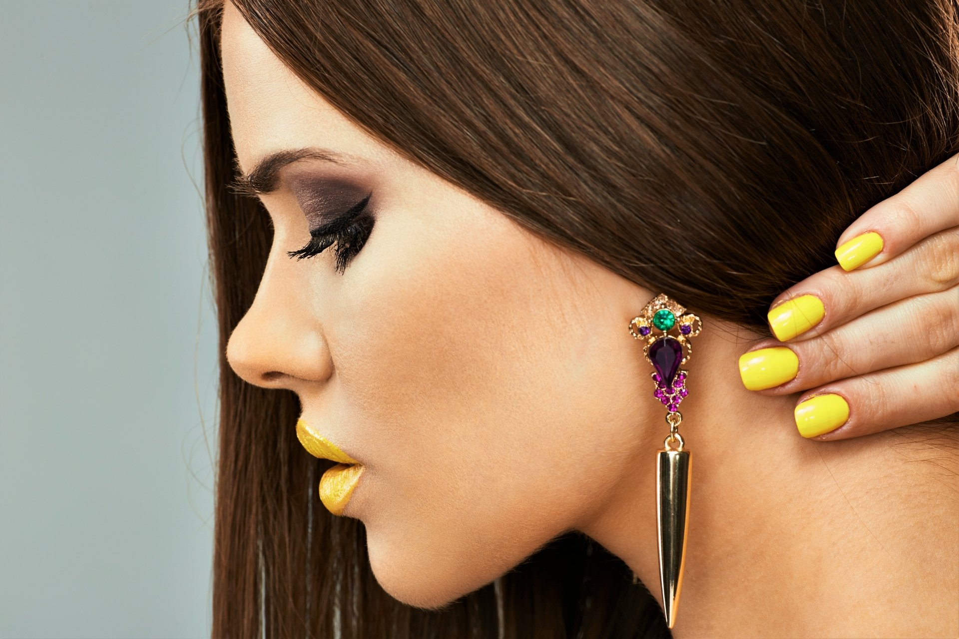 4K Ultra HD PC desktop wallpaper — close-up profile of a woman with long brown hair, yellow nails and matching lipstick, smoky eye makeup and a jeweled spike earring.