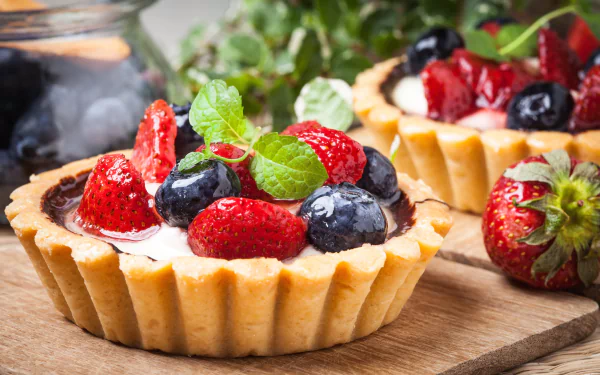 Close-up of a blueberry and strawberry tart with fresh berries and mint leaves, displayed as a vibrant 4K Ultra HD dessert wallpaper.