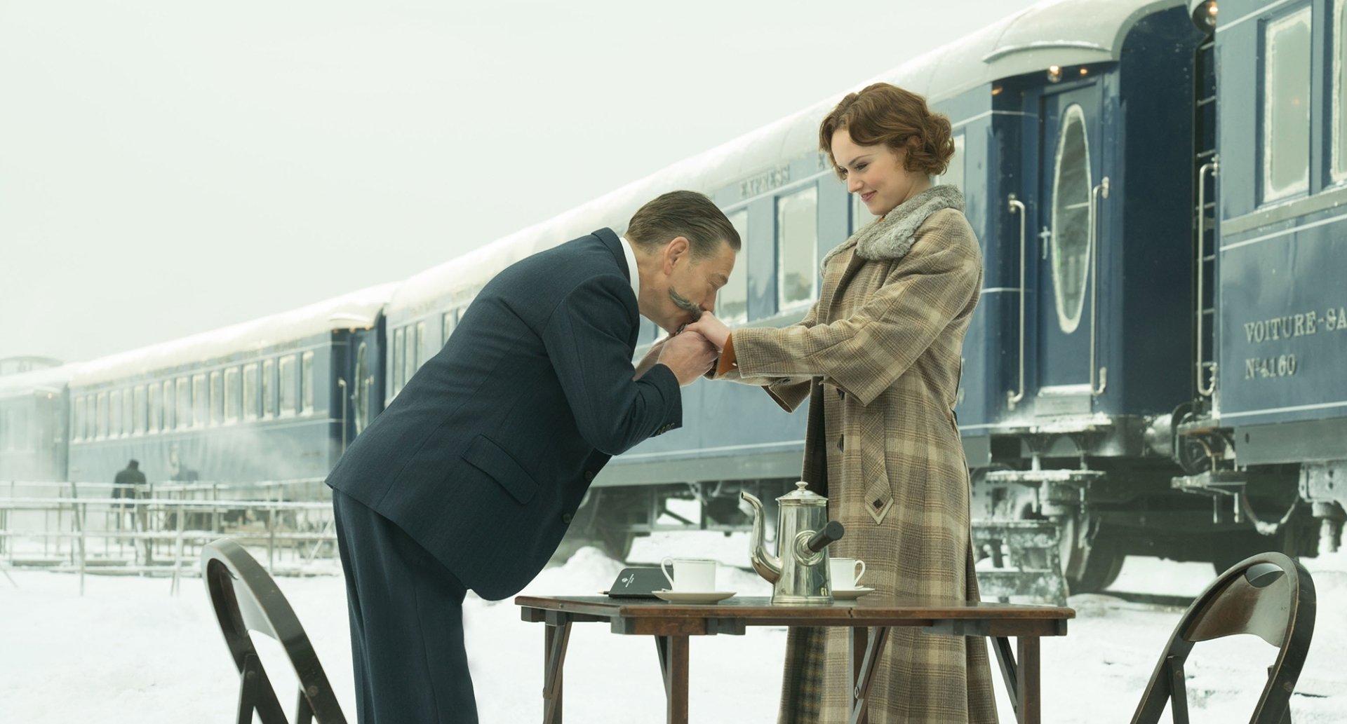 HD desktop wallpaper featuring Daisy Ridley and Kenneth Branagh in a scene from Murder on the Orient Express (2017), set against the backdrop of a classic train in a snowy landscape.