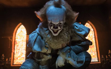 HD desktop wallpaper featuring Pennywise the clown from the movie It (2017), based on Stephen King's novel. The image captures a creepy and intense scene with Pennywise in a dark setting.
