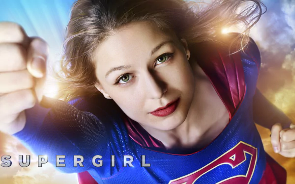 HD desktop wallpaper of Melissa Benoist as Supergirl from the TV show, featuring her in a dynamic flying pose with sunlight and a clear blue sky background.