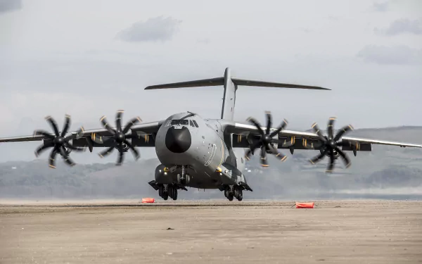 A high-definition wallpaper featuring the Airbus A400M military transport aircraft taking off from a runway, with mountains and a cloudy sky in the background.