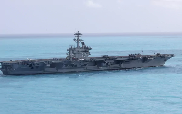 Aircraft carrier USS Abraham Lincoln (CVN-72) sailing on turquoise sea beneath a clear horizon — military warship 2K Quad HD desktop wallpaper