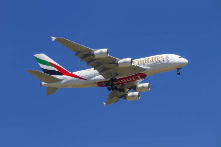 HD wallpaper featuring an Airbus A380 passenger plane from Emirates, flying against a clear blue sky.
